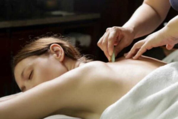 Discover the Healing Benefits of Traditional Chinese Massage in Tysons Corner Close-up of Gua Sha therapy, a Traditional Chinese massage Tysons Corner technique, being applied to a woman's back.